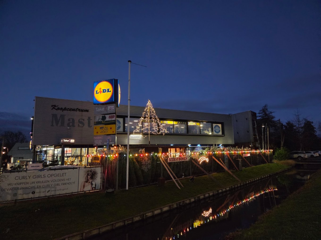 Sfeervol verlicht Koopcentrum Mast en verkoopplein met de kerstboom in de avond aan de singel